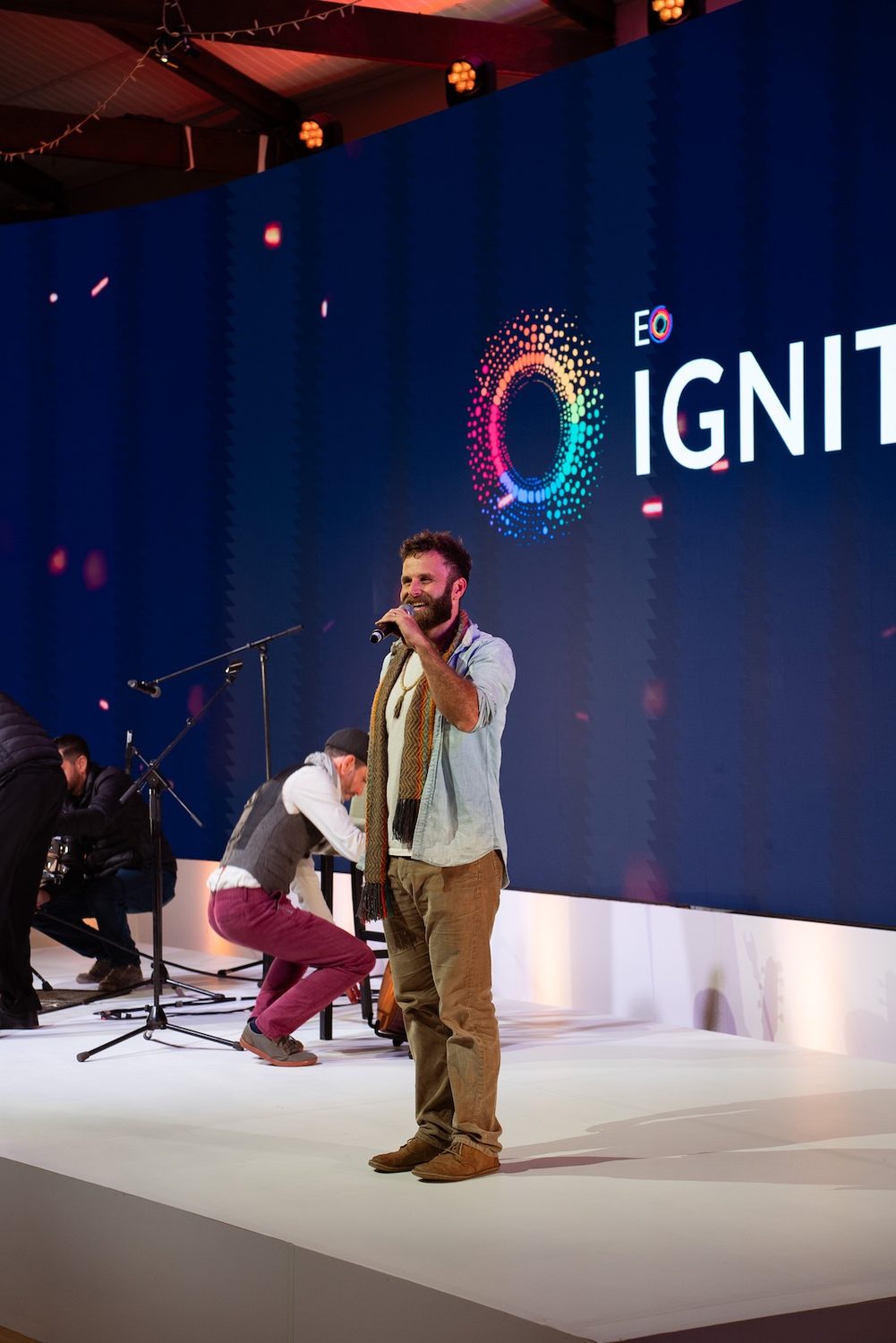 Nathan Maingard performing on stage at EO Ignite with the EO Ignite logo behind him